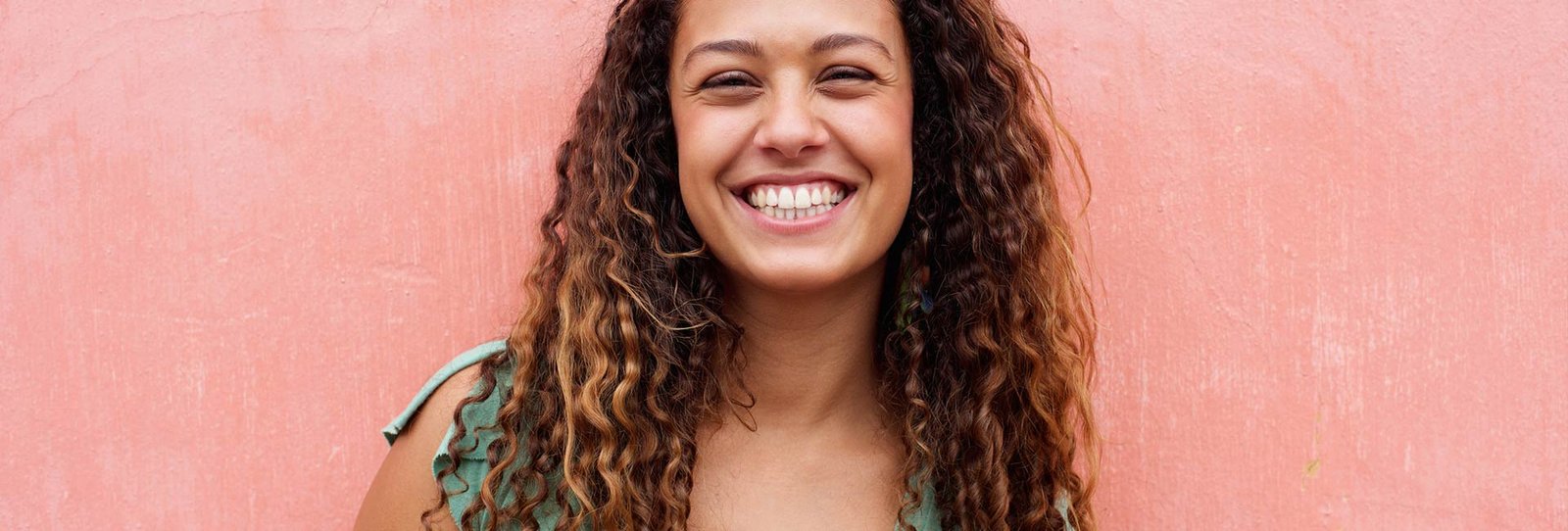 A beautiful young woman in pink background smiling at the camera